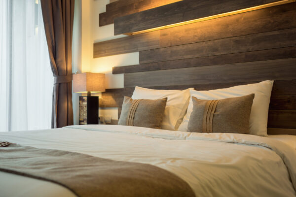 Empty double bed and lamp on side of bed in luxury and natural style bedroom is decorated with wooden boards.